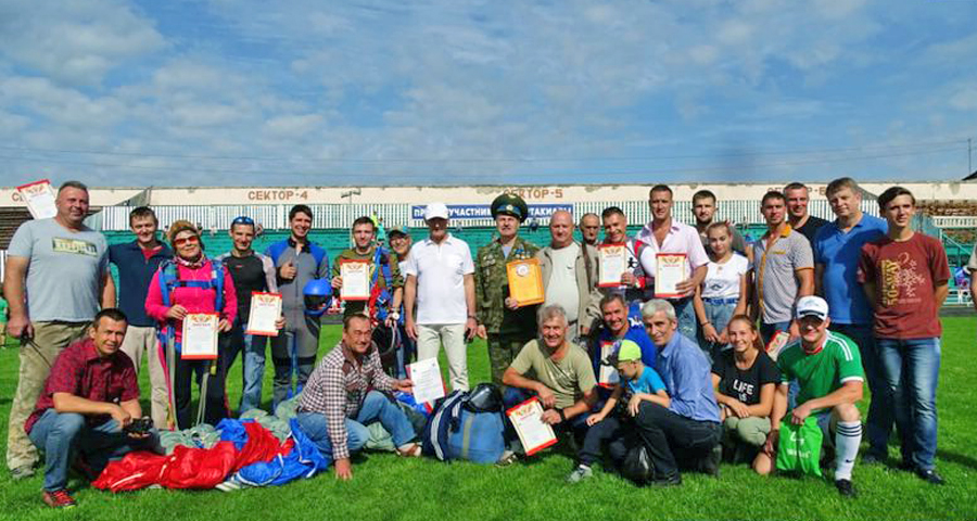 В День Воздушного флота - разноцветные купола парашютов и флаг России в небе над Арсеньевом